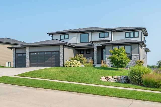 prairie-style house with concrete driveway, a front lawn, an attached garage, and stone siding