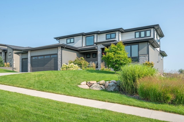 prairie-style house featuring an attached garage, a front lawn, stone siding, and stucco siding