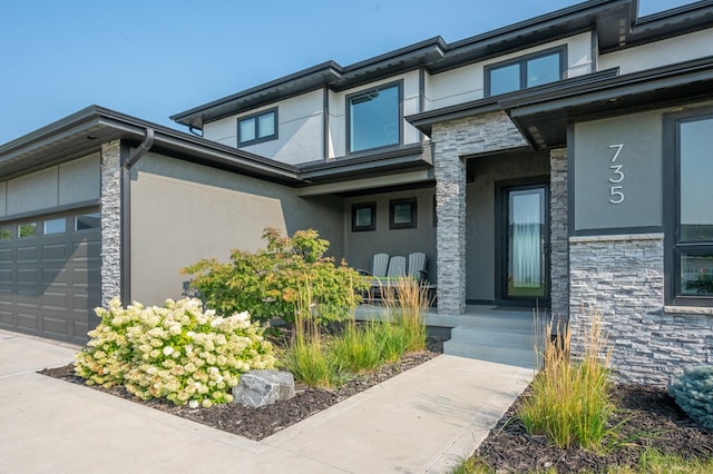 property entrance featuring stucco siding, covered porch, an attached garage, and stone siding
