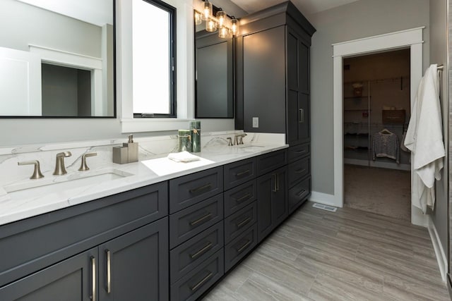 bathroom with double vanity, visible vents, a spacious closet, and a sink