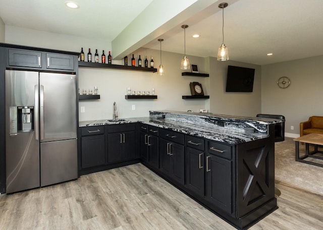 kitchen with light stone counters, open shelves, a sink, light wood finished floors, and stainless steel refrigerator with ice dispenser