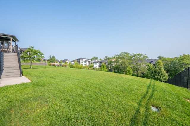 view of yard with fence, stairs, and a residential view