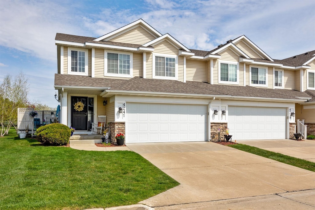 4241 153rd St, Urbandale, IA 50323 - view of front of property featuring a shingled roof, a garage, stone siding, a front lawn, and concrete driveway