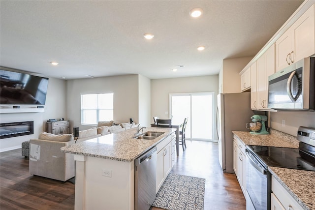 kitchen with dark wood finished floors, stainless steel appliances, a kitchen island with sink, and white cabinetry