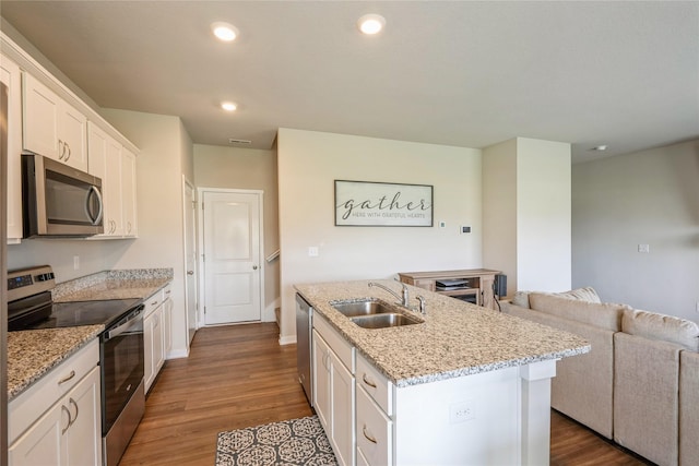 kitchen with a sink, appliances with stainless steel finishes, dark wood-style floors, open floor plan, and an island with sink