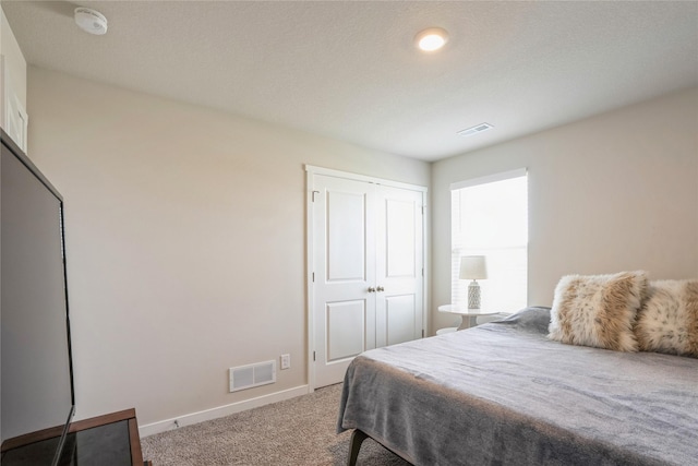 carpeted bedroom with visible vents, a closet, and baseboards