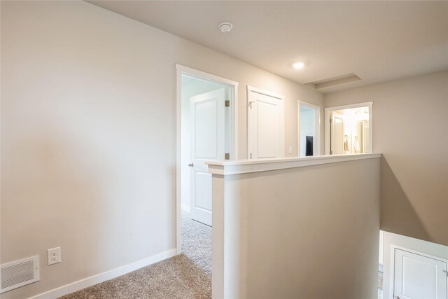 corridor with visible vents, carpet, and baseboards