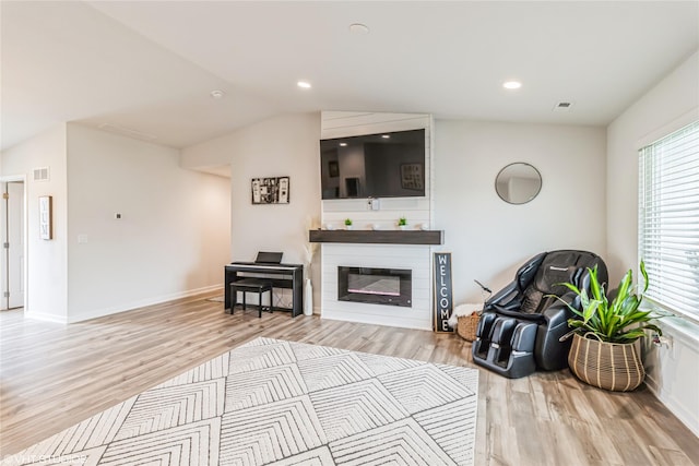 living room featuring visible vents, light wood-type flooring, a fireplace, and baseboards