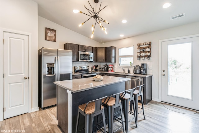 kitchen featuring appliances with stainless steel finishes, a breakfast bar, visible vents, dark brown cabinetry, and light wood-type flooring