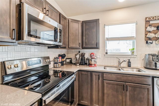 kitchen with a sink, appliances with stainless steel finishes, tasteful backsplash, light stone counters, and dark brown cabinets