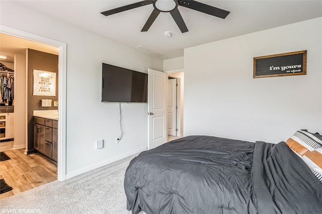 bedroom with baseboards, light carpet, connected bathroom, and ceiling fan