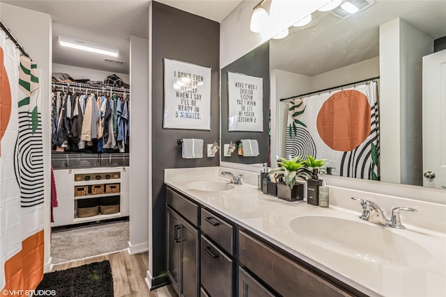 full bathroom featuring double vanity, a sink, wood finished floors, and visible vents