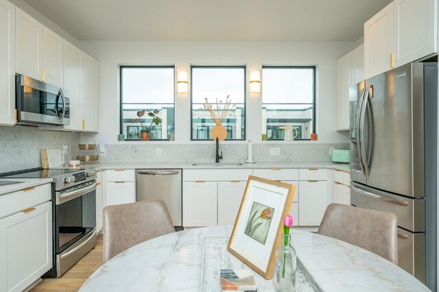 kitchen with light stone counters, a sink, appliances with stainless steel finishes, and a healthy amount of sunlight