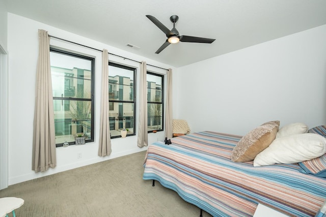 carpeted bedroom featuring a ceiling fan and visible vents
