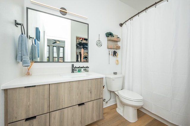 full bathroom with a shower with shower curtain, toilet, wood finished floors, and vanity