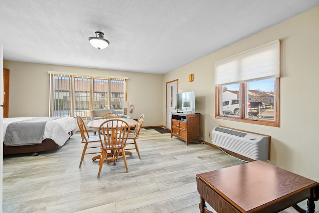 dining space with a wealth of natural light, light wood-style floors, an AC wall unit, and baseboards