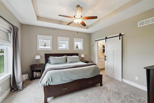 bedroom with a barn door, light carpet, baseboards, visible vents, and a raised ceiling