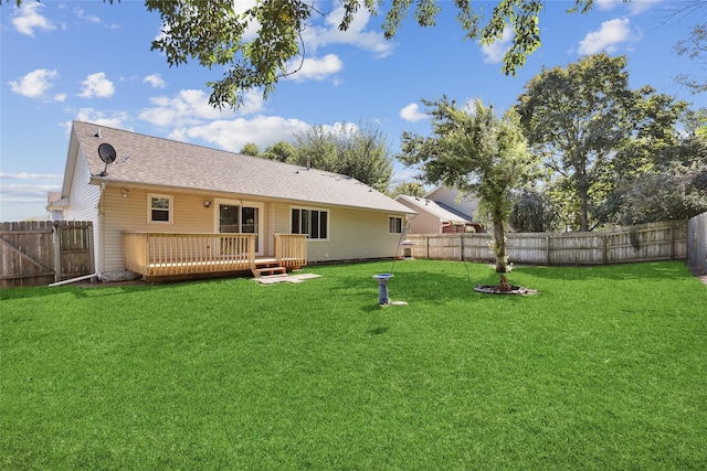 back of property with roof with shingles, a deck, a yard, and a fenced backyard