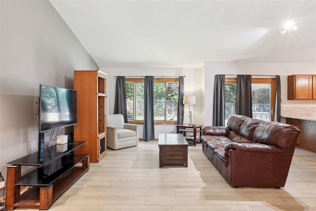 living room with vaulted ceiling, light wood-style flooring, and a healthy amount of sunlight