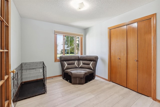 sitting room featuring a textured ceiling and light wood-style flooring