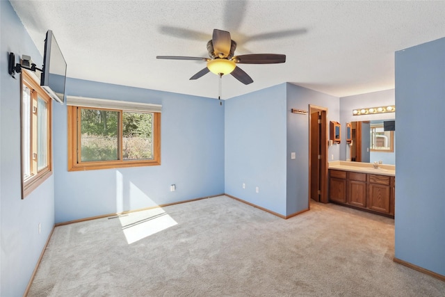 unfurnished bedroom with a textured ceiling, a sink, light colored carpet, and baseboards