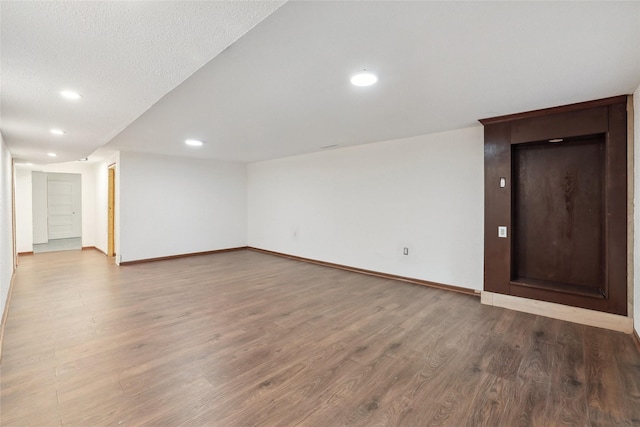 below grade area featuring recessed lighting, wood finished floors, and baseboards