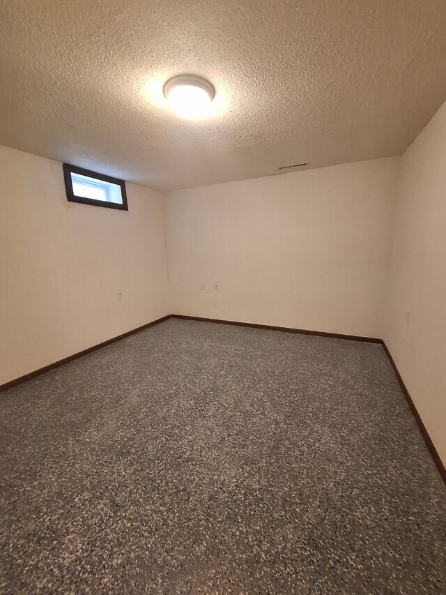 spare room featuring baseboards and a textured ceiling
