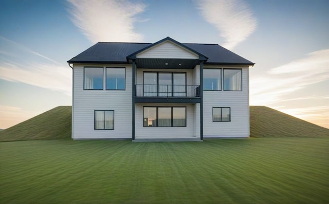 back of house with a lawn and a balcony