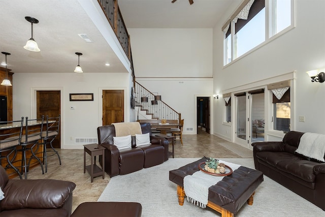 living room featuring a high ceiling, visible vents, stairway, and baseboards