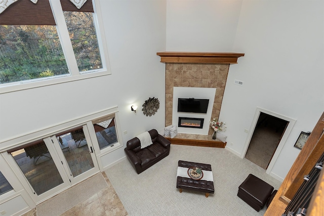 living area featuring a towering ceiling, baseboards, and a glass covered fireplace
