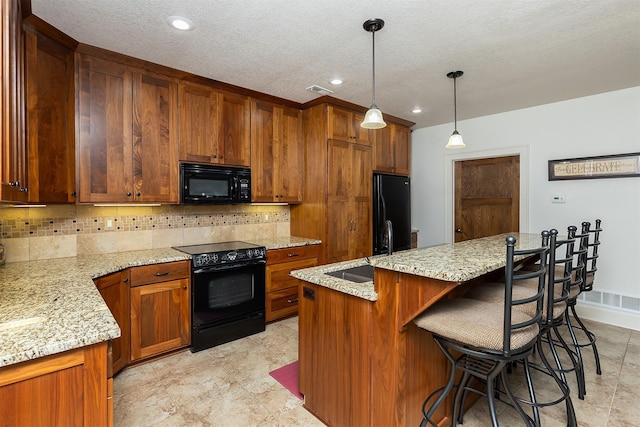 kitchen with light stone countertops, brown cabinetry, black appliances, backsplash, and a sink