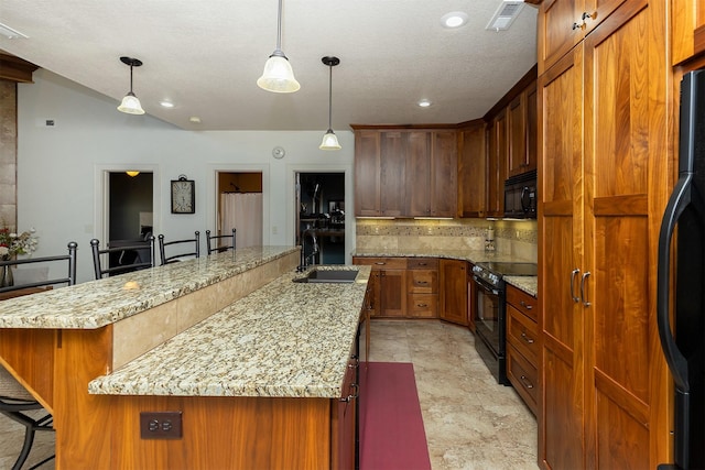 kitchen featuring a sink, a kitchen breakfast bar, tasteful backsplash, black appliances, and visible vents
