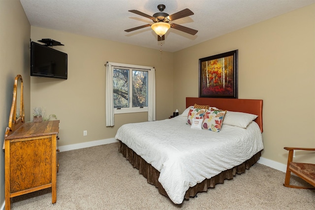 carpeted bedroom with a textured ceiling, ceiling fan, and baseboards