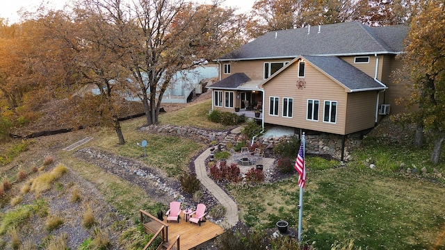 back of property featuring a lawn, roof with shingles, a fire pit, and a wooden deck