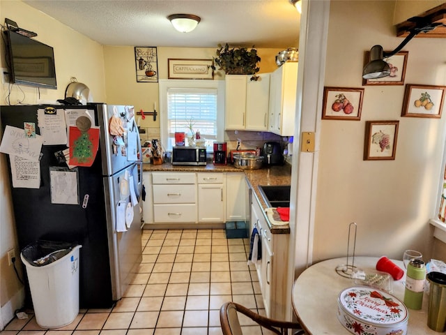 1134 39th St, Des Moines, IA 50311 - kitchen featuring light tile patterned floors, backsplash, white cabinetry, dark countertops, and appliances with stainless steel finishes