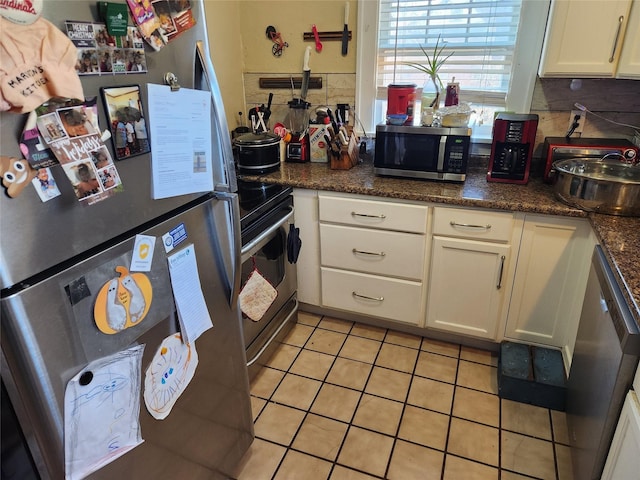 1134 39th St, Des Moines, IA 50311 - kitchen featuring appliances with stainless steel finishes, light tile patterned flooring, white cabinetry, and decorative backsplash