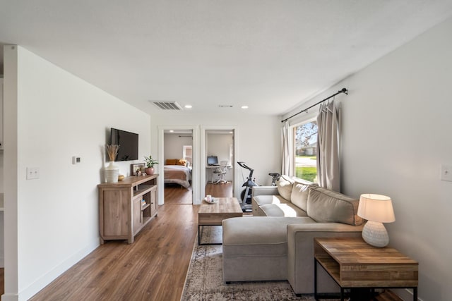 living area with recessed lighting, visible vents, wood finished floors, and baseboards
