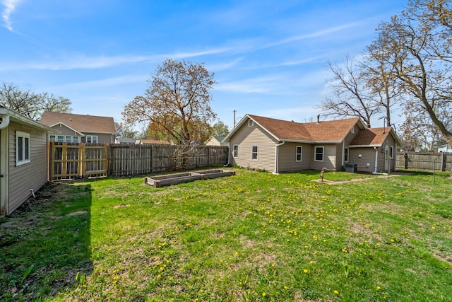 view of yard with a vegetable garden, central AC, and a fenced backyard