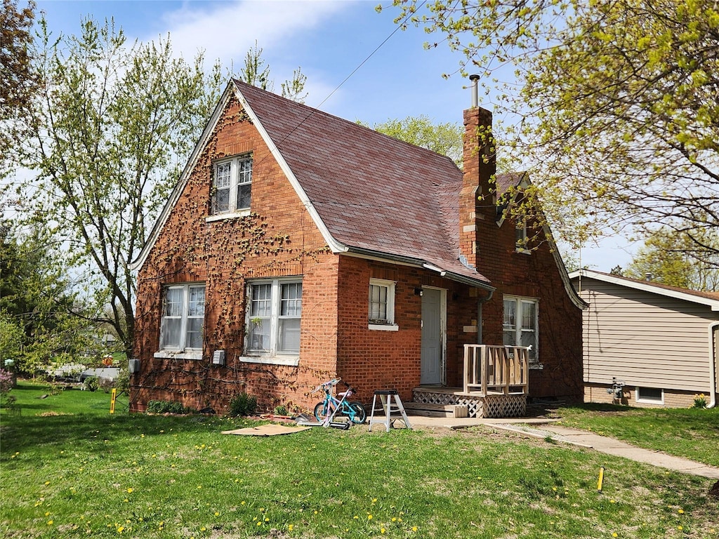 view of front facade with a chimney, a front yard, and brick siding