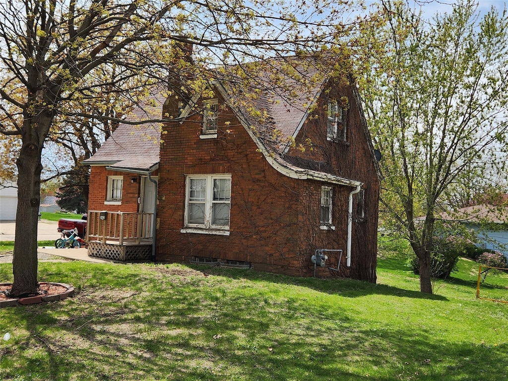 view of side of property with a lawn, a chimney, and a shingled roof