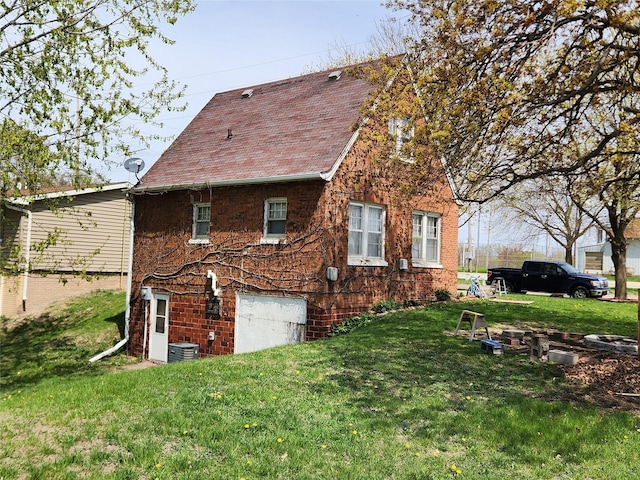 view of property exterior with a lawn, roof with shingles, central AC unit, and brick siding