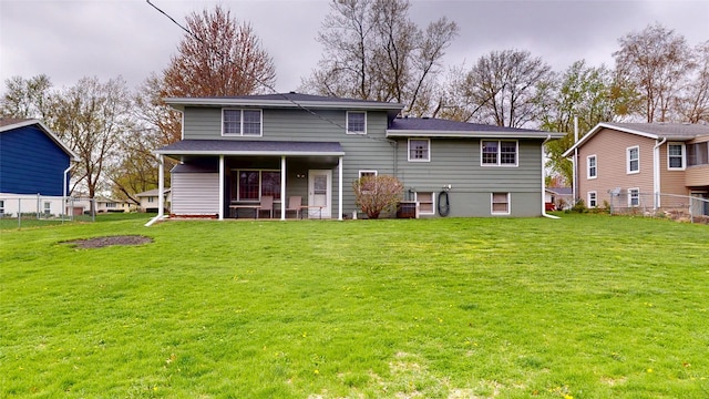 back of property with a lawn and fence