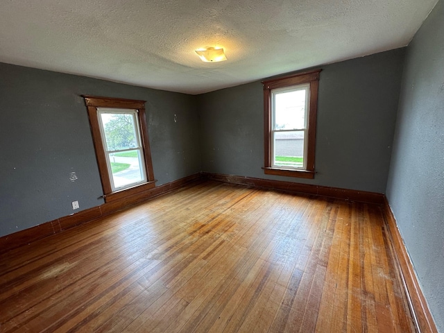 spare room with baseboards, a textured ceiling, and wood-type flooring