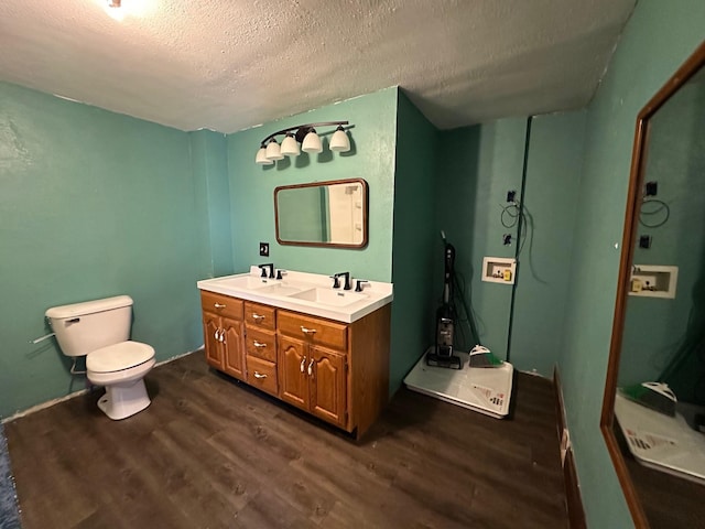 full bathroom with a sink, toilet, double vanity, a textured ceiling, and wood finished floors