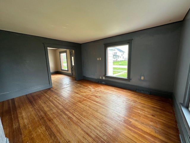 empty room featuring wood finished floors, visible vents, and baseboards