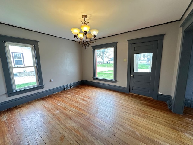 unfurnished dining area featuring baseboards, visible vents, a notable chandelier, and light wood-style flooring