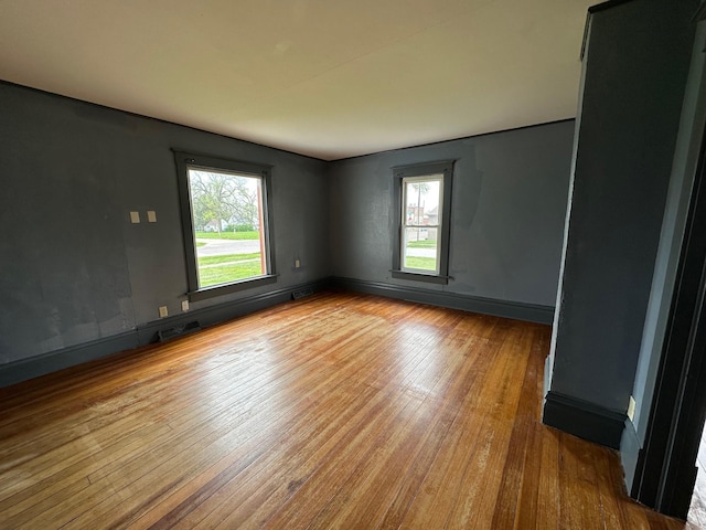 unfurnished room featuring visible vents, baseboards, and wood-type flooring