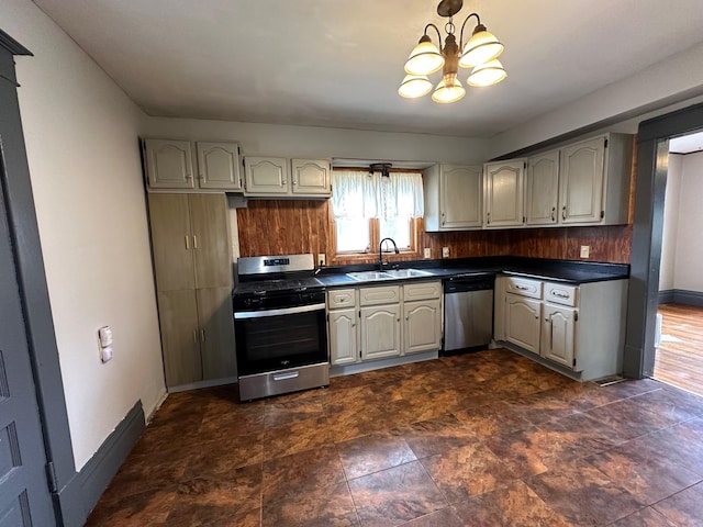 kitchen featuring a sink, appliances with stainless steel finishes, dark countertops, baseboards, and a notable chandelier