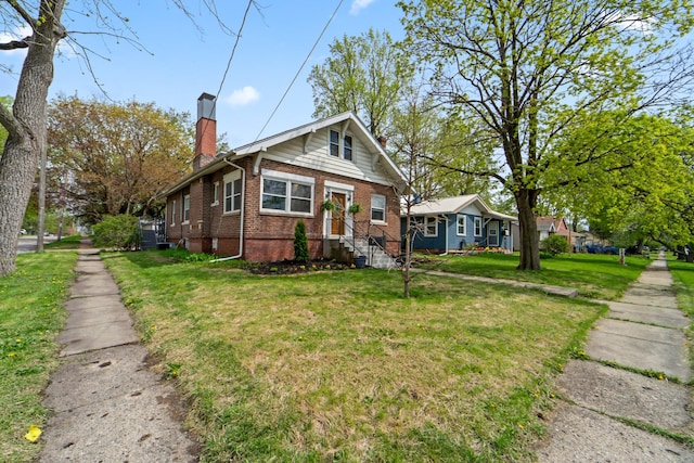 bungalow with a front yard, a chimney, and brick siding