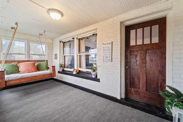 sunroom / solarium featuring wood ceiling, brick wall, and carpet floors